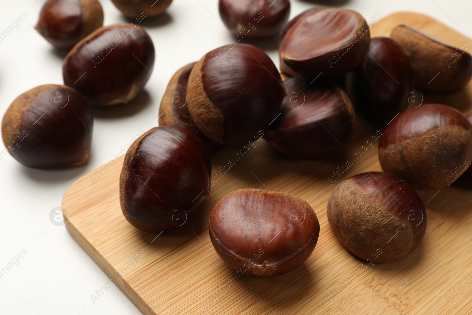 Photo of Sweet fresh edible chestnuts on white table, closeup