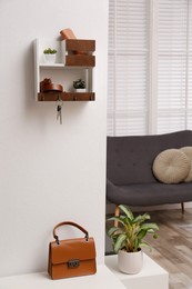 Photo of Hallway interior with stylish furniture, accessories and wooden hanger for keys on white wall