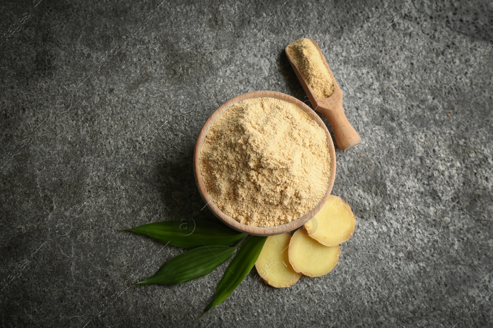 Photo of Dry ginger powder, fresh root and leaves on grey table, flat lay