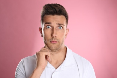 Emotional young man with double chin on pink background