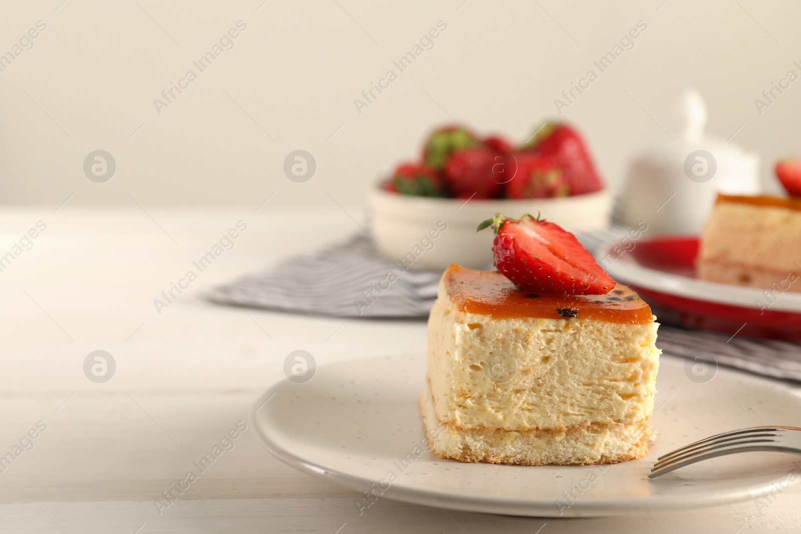 Photo of Piece of cheesecake with strawberry and fork on white table, closeup with space for text