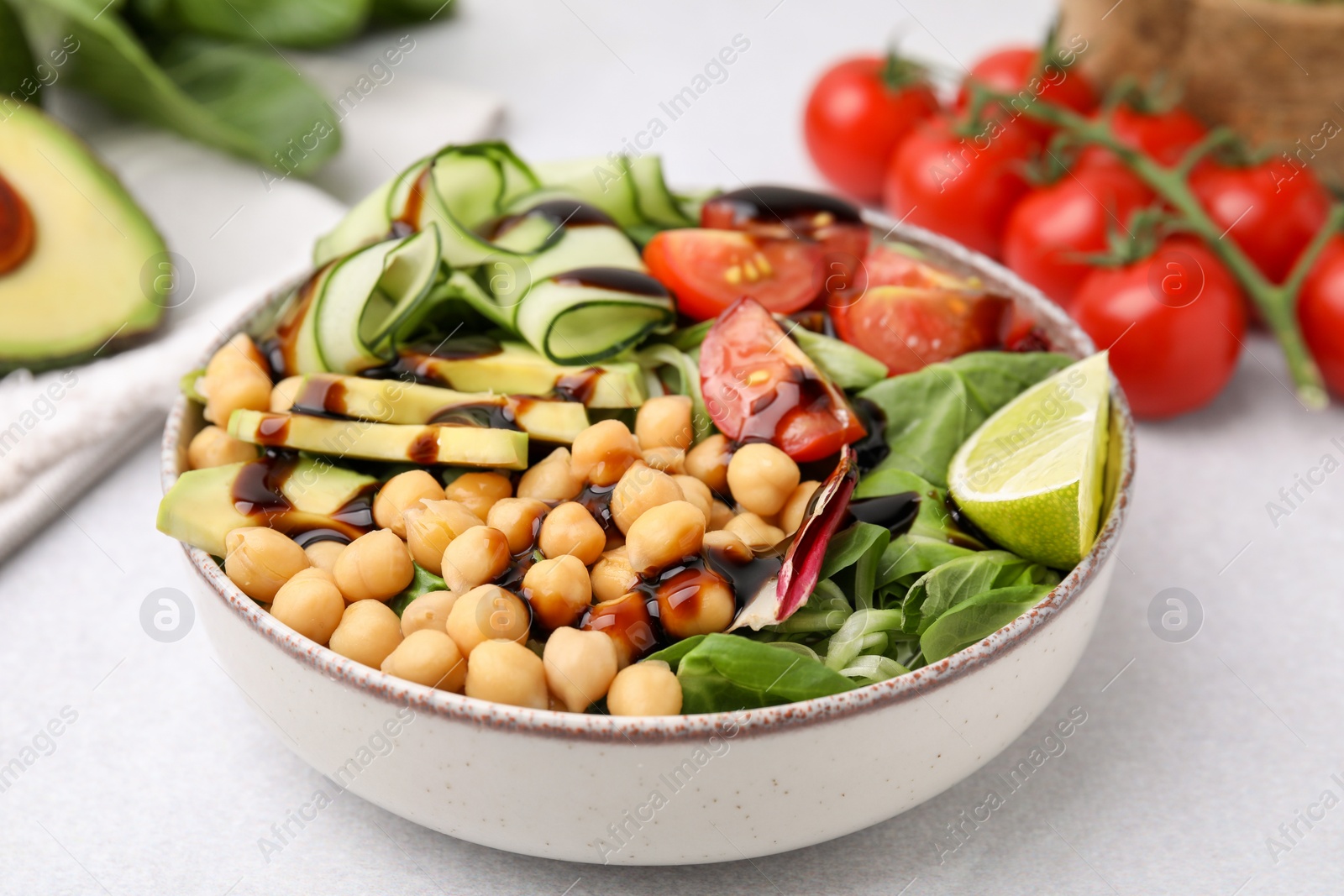 Photo of Delicious salad with chickpeas, vegetables and balsamic vinegar on white table, closeup