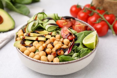 Delicious salad with chickpeas, vegetables and balsamic vinegar on white table, closeup