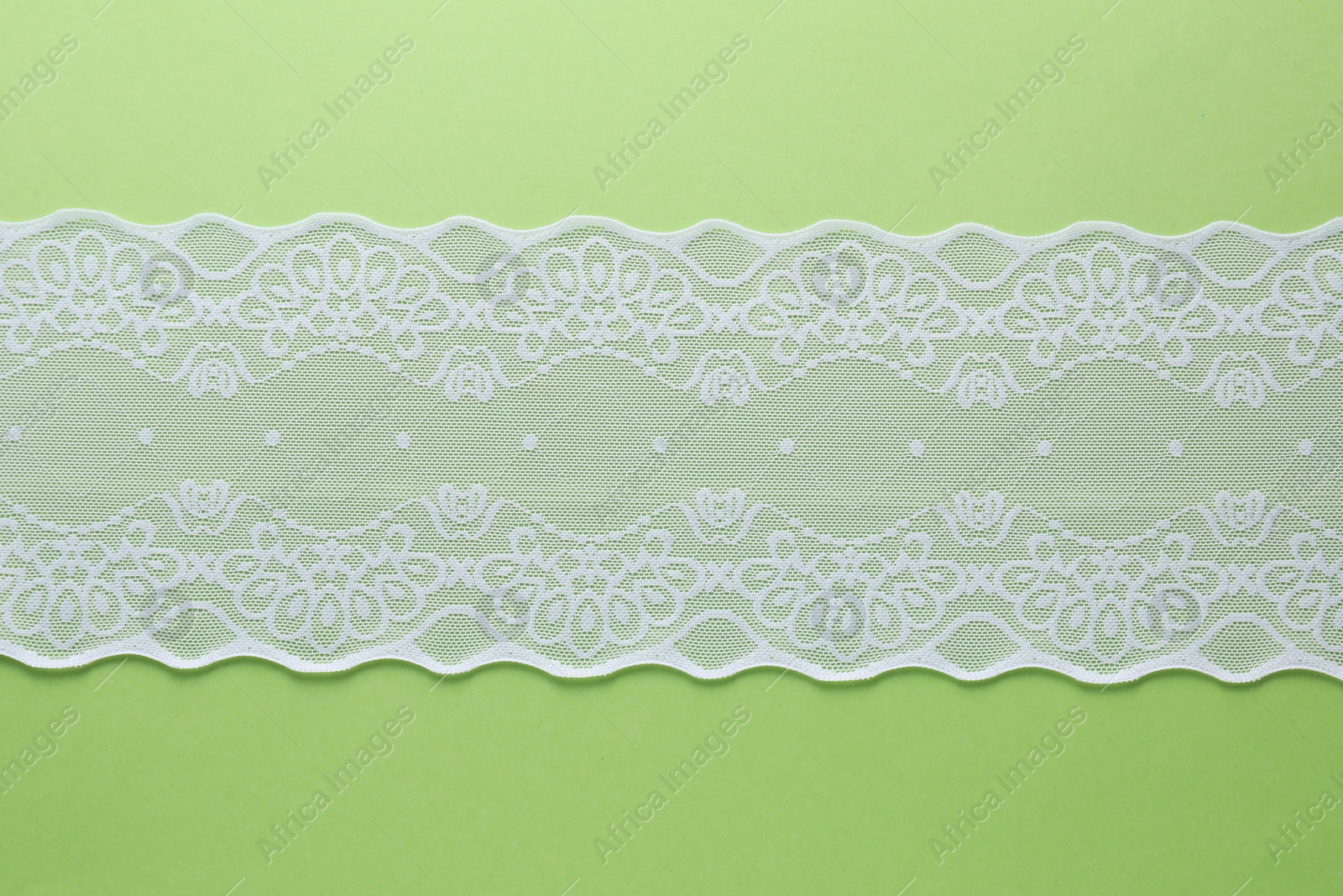 Photo of White lace on green background, top view