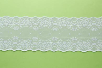 Photo of White lace on green background, top view