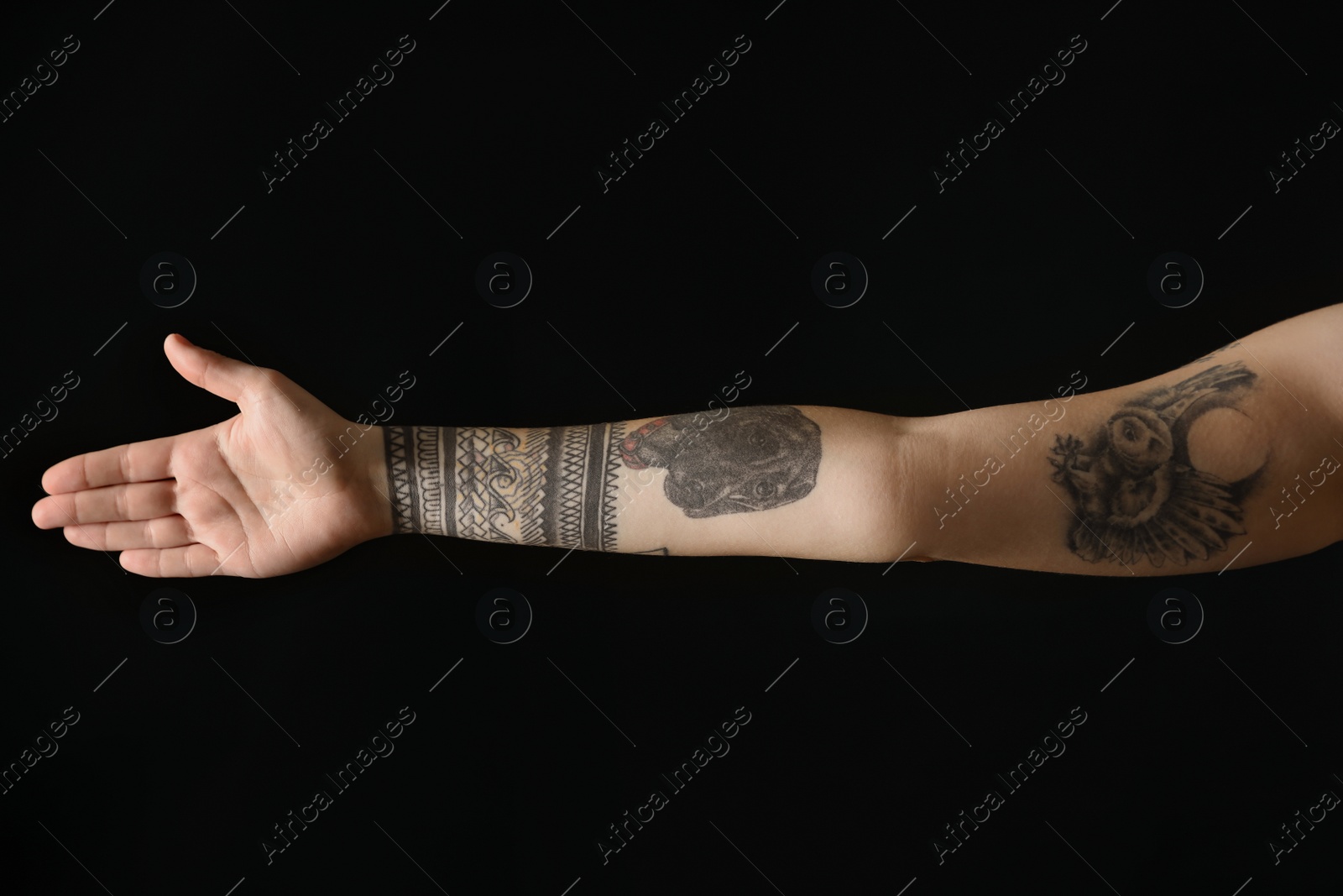 Photo of Woman with stylish tattoos on arm against black background, closeup