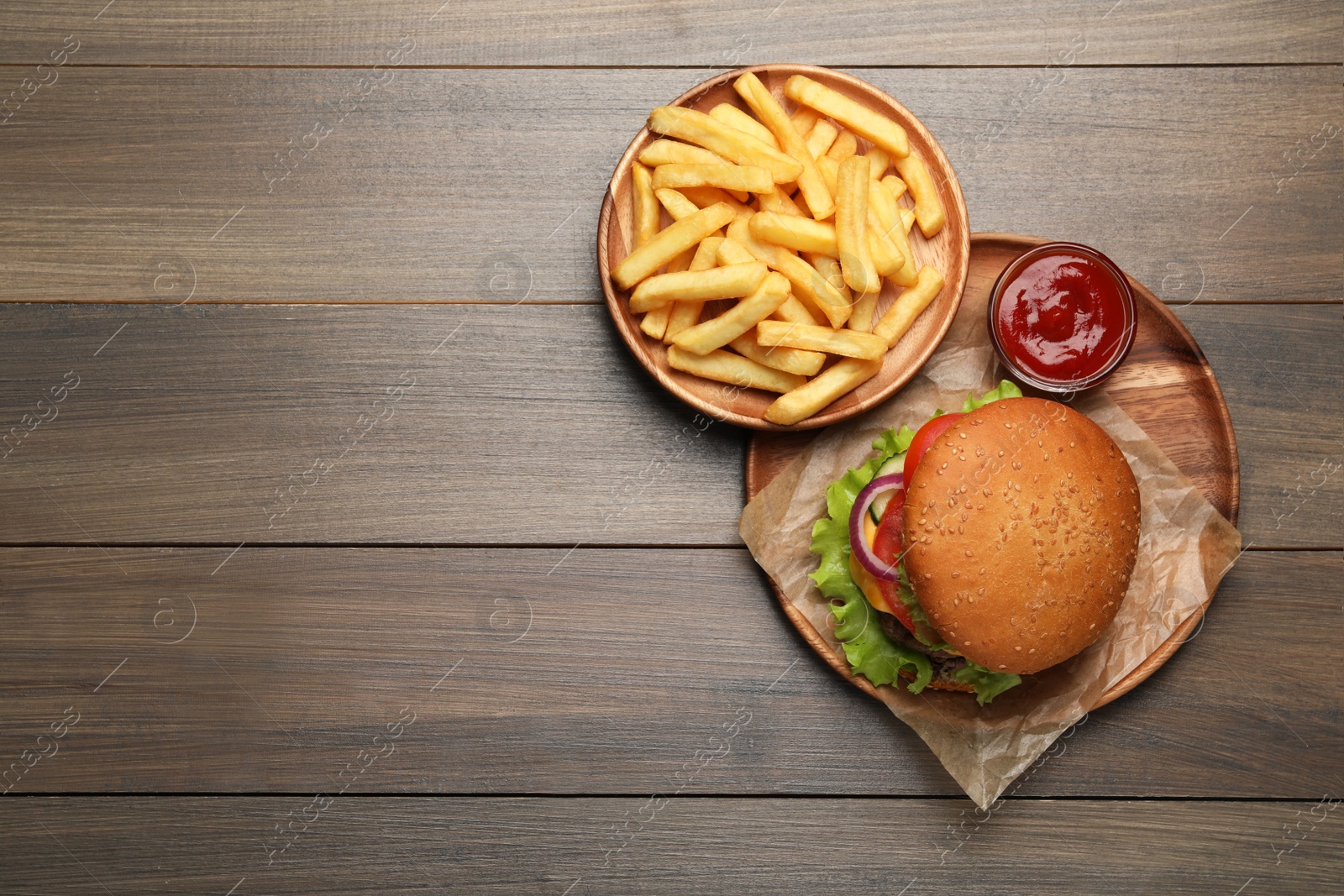 Photo of French fries, tasty burger and sauce on wooden table, flat lay. Space for text