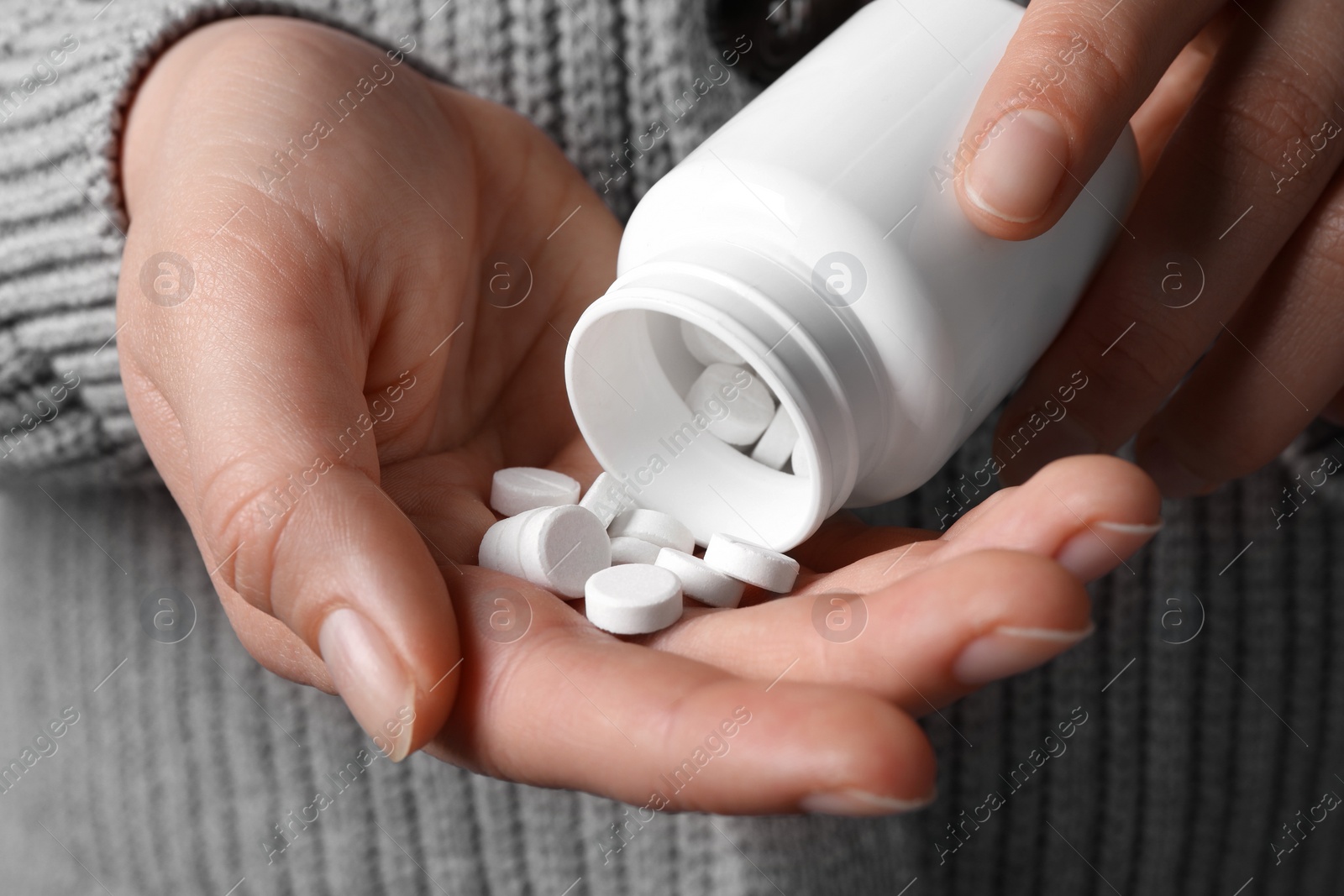 Photo of Woman pouring pills from bottle, closeup view