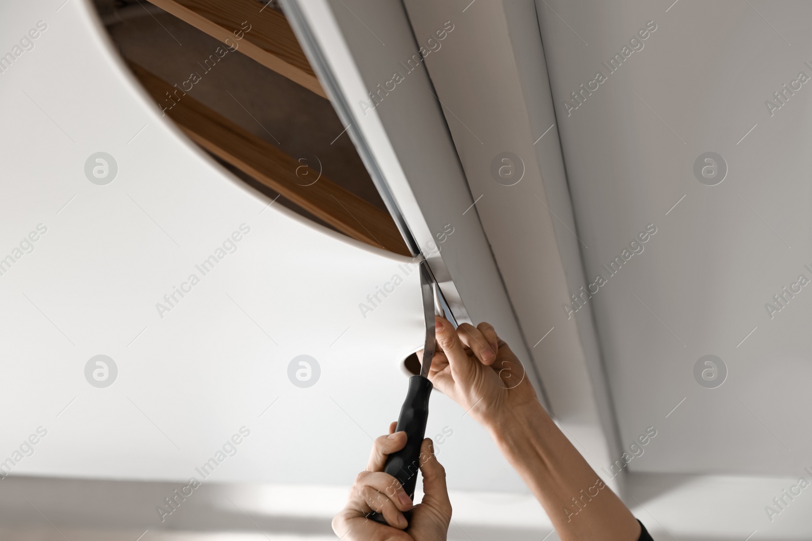 Photo of Repairman installing white stretch ceiling in room, closeup