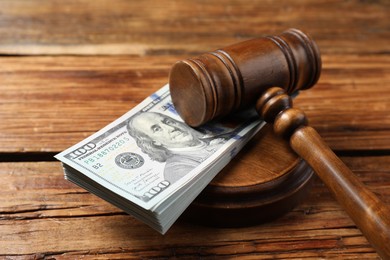 Photo of Judge's gavel and money on wooden table, closeup