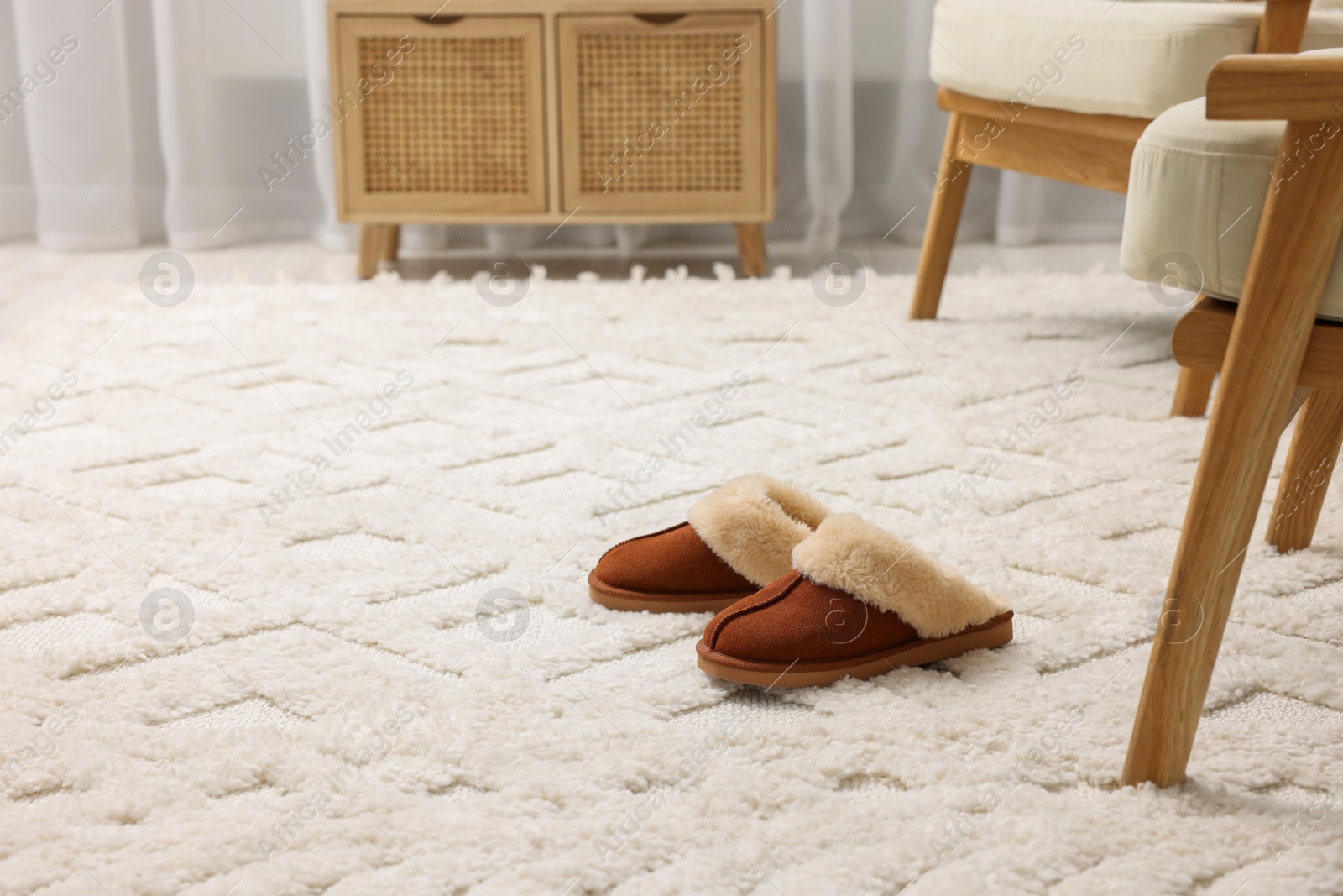 Photo of Slippers on soft white carpet in living room