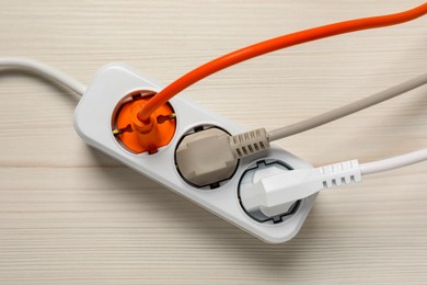 Photo of Extension cord with electrical plugs on white wooden floor, top view. Electrician's equipment