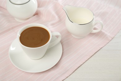 Cup of aromatic coffee and milk on white wooden table