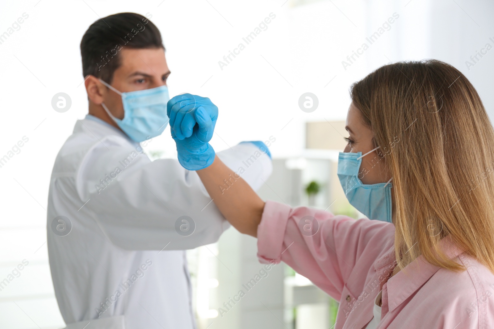 Photo of Doctor and patient doing elbow bump instead of handshake in clinic. New greeting during COVID-19 pandemic