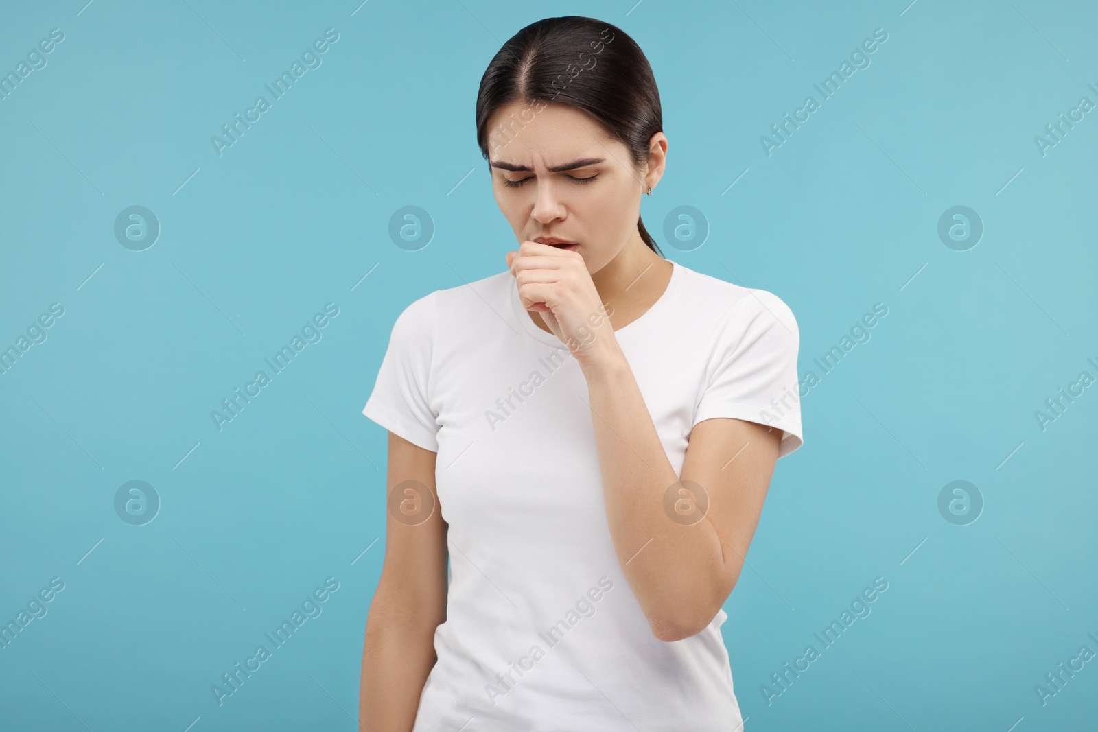 Photo of Woman coughing on light blue background. Cold symptoms