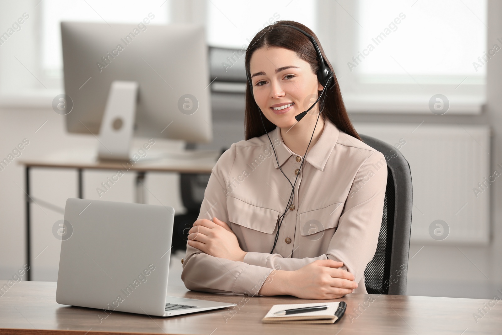 Photo of Hotline operator with headset working on laptop in office