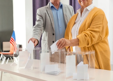 Elderly people putting ballot papers into boxes at polling station