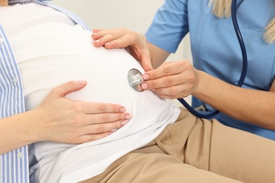 Photo of Pregnancy checkup. Doctor with stethoscope listening baby's heartbeat in patient's tummy in clinic, closeup