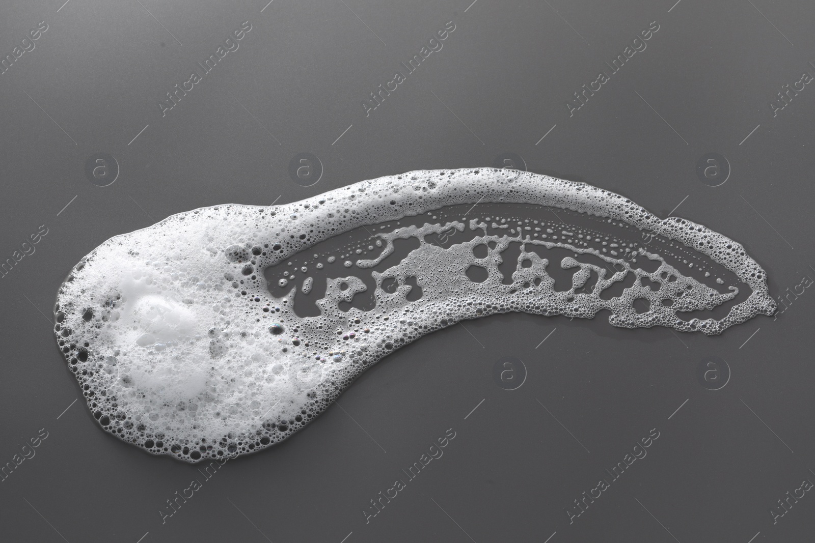 Photo of Smudge of white washing foam on dark gray background, top view