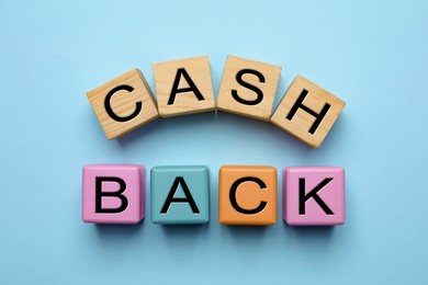 Photo of Word Cashback made with cubes on light blue background, flat lay