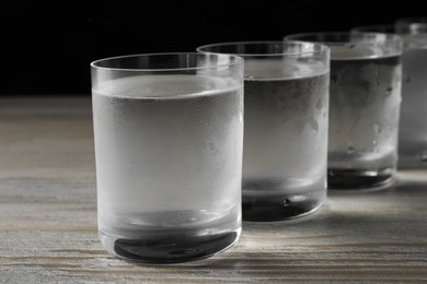 Photo of Shot glasses of cold vodka on wooden table, closeup