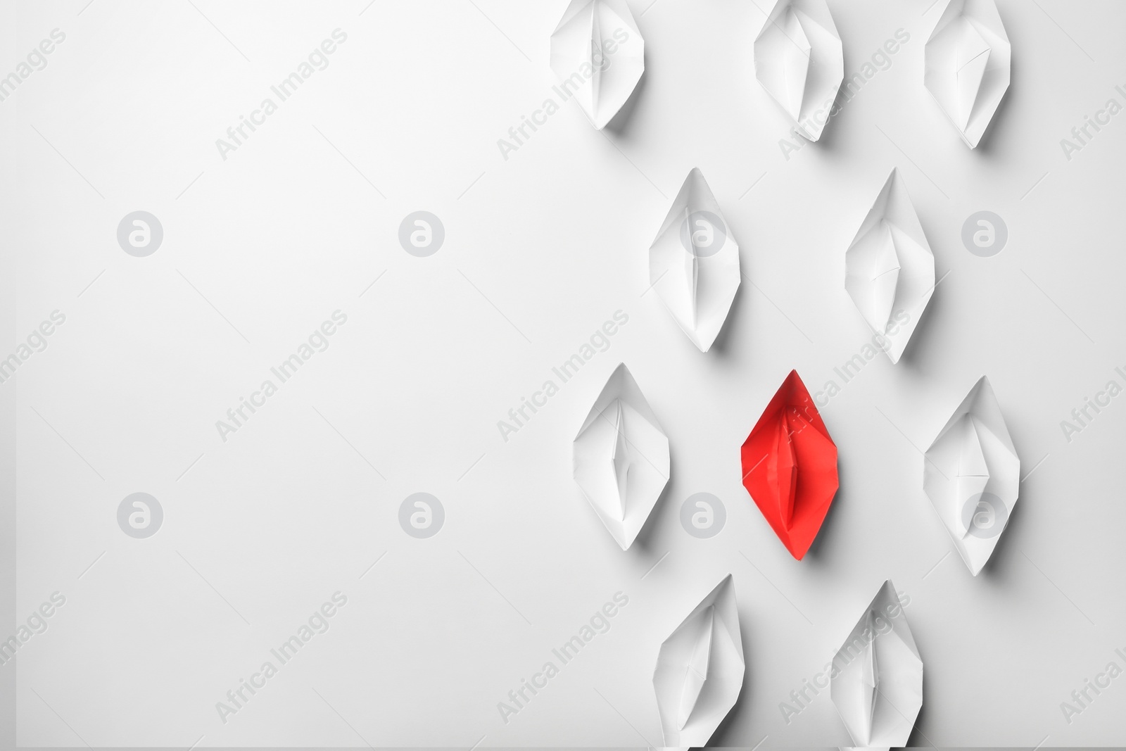 Photo of Red paper boat among others on white background, flat lay with space for text. Uniqueness concept
