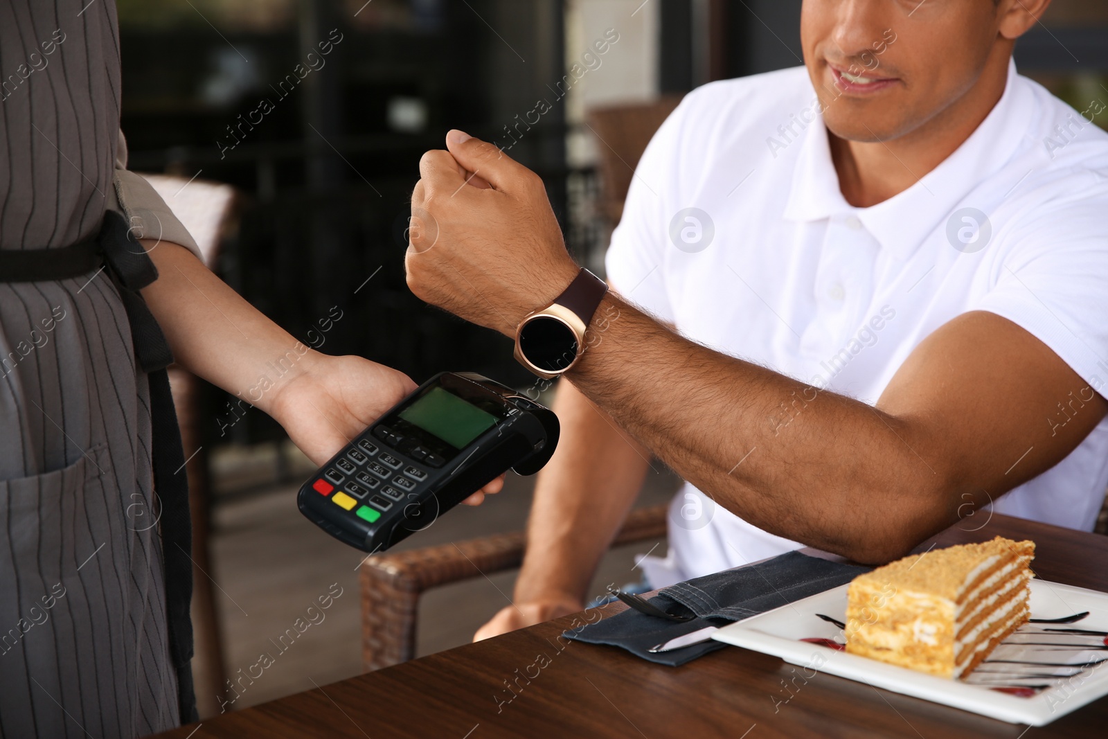 Photo of Man making payment with smart watch in cafe, closeup