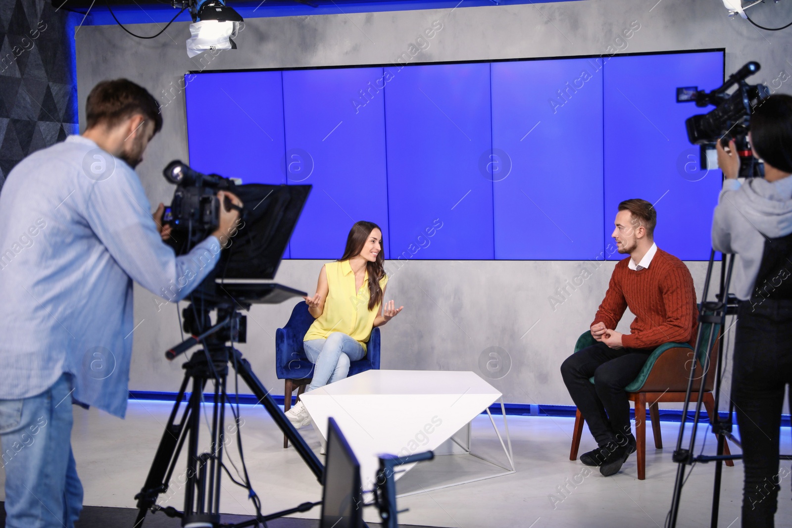 Photo of Presenters and video camera operator working in studio. News broadcasting