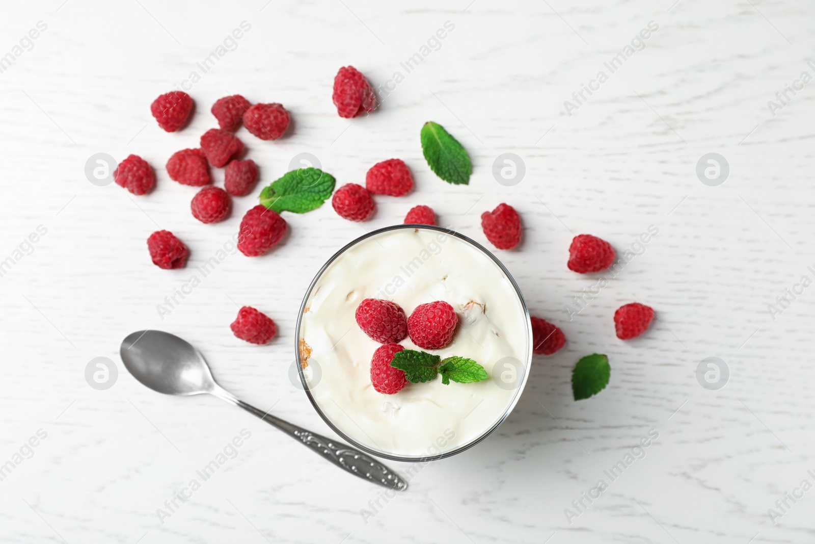 Photo of Delicious dessert with raspberries in glass on wooden table, top view