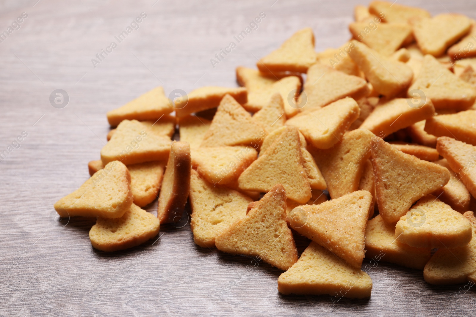 Photo of Heap of crispy rusks on wooden table, closeup