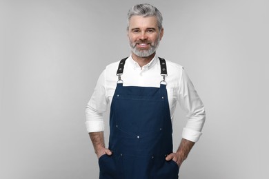 Photo of Happy man wearing kitchen apron on grey background. Mockup for design