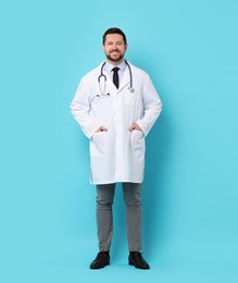 Photo of Smiling doctor with stethoscope on light blue background