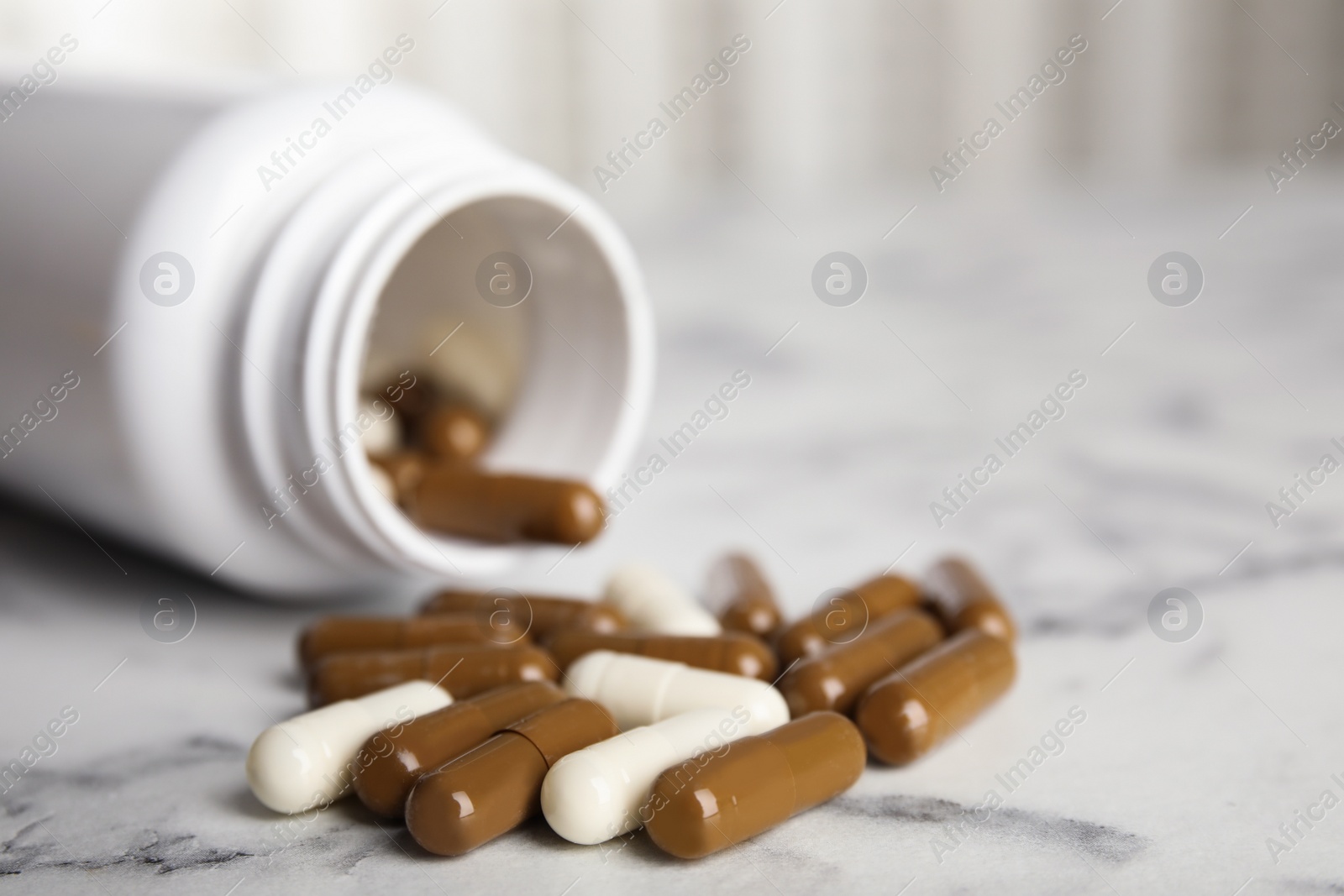 Photo of Bottle with vitamin pills on white marble table, closeup