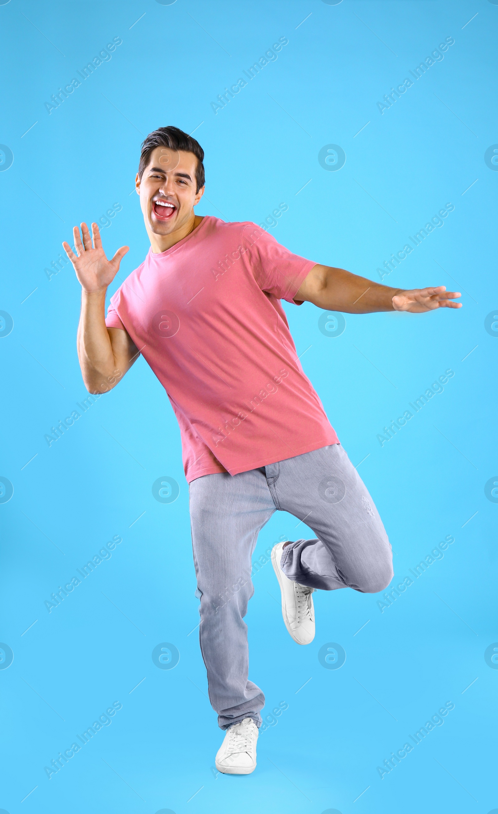 Photo of Handsome young man dancing on blue background