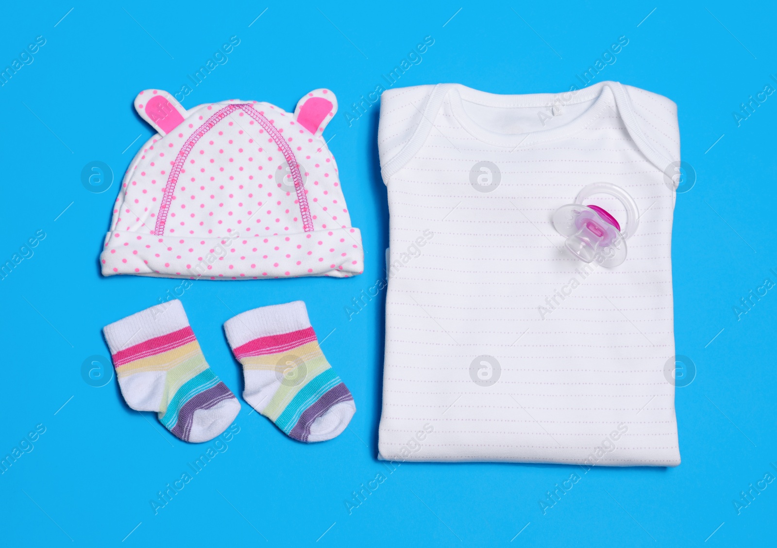 Photo of Flat lay composition with baby clothes and pacifier on blue background