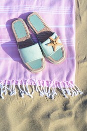 Pink blanket with stylish slippers and dry starfish on sandy beach, top view
