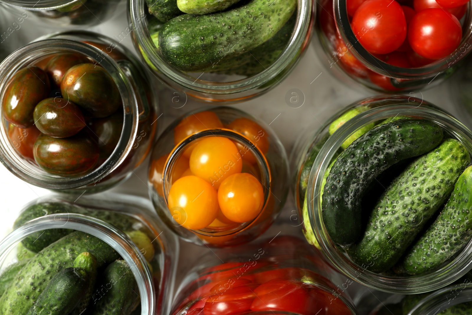 Photo of Pickling jars with fresh vegetables on white marble table, flat lay