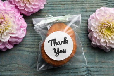 Photo of Bag of cookies with phrase Thank you and flowers on grey wooden table, flat lay