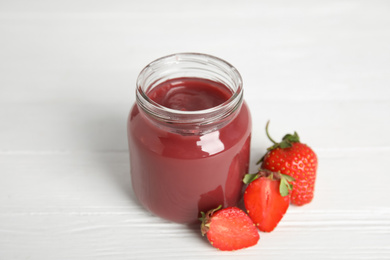 Photo of Healthy baby food in jar and fresh strawberries on white wooden table