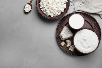 Clay dishware with fresh dairy products on grey table, flat lay. Space for text