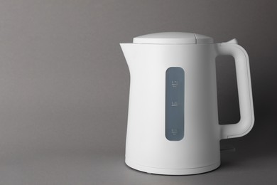 New modern electric kettle on grey background, space for text
