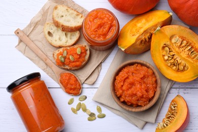 Delicious pumpkin jam and fresh pumpkin on white wooden table, flat lay