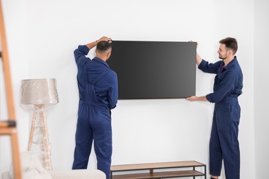 Male movers carrying plasma TV in new house