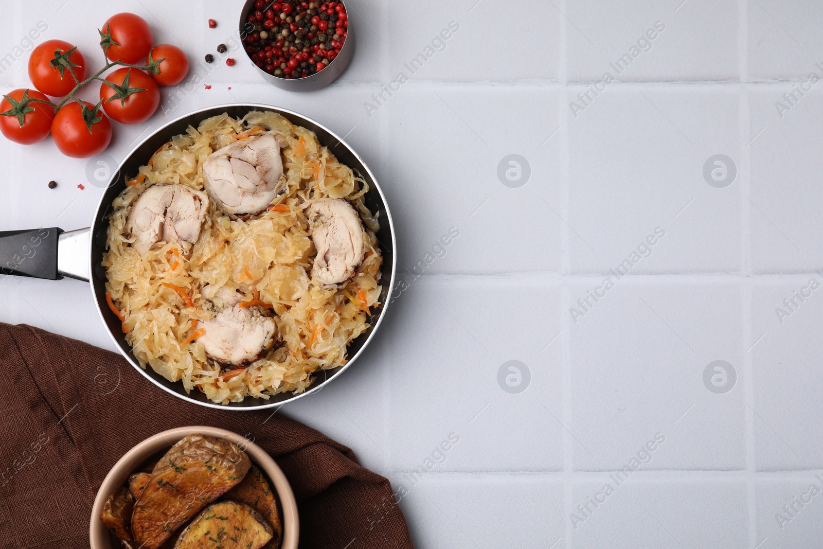 Photo of Frying pan with sauerkraut, chicken and products on white tiled table, flat lay. Space for text