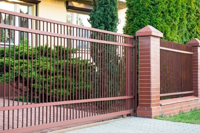 Photo of Beautiful brick fence with brown iron railing outdoors