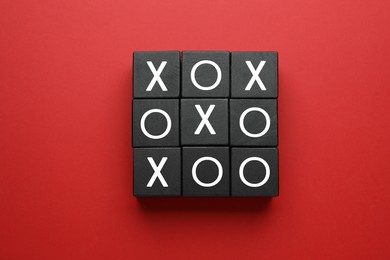 Photo of Tic tac toe cube set on red background, flat lay