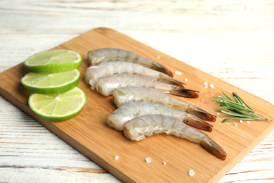 Photo of Fresh raw shrimps with rosemary and lime on white wooden table
