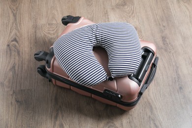 Photo of Striped travel pillow and suitcase on floor