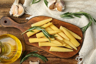 Photo of Fresh baby corn cobs on wooden table, flat lay