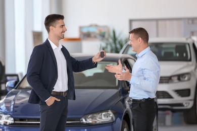 Young salesman working with client in car dealership